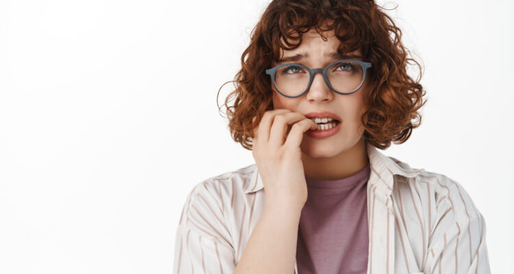 woman-biting-fingernails-looking-up-nervous-feeling-worried-as-looking-top-panicking-standing-white