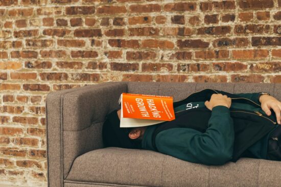 man sleeping on couch with a book on his face