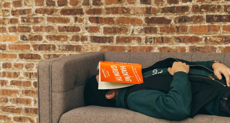 man sleeping on couch with a book on his face