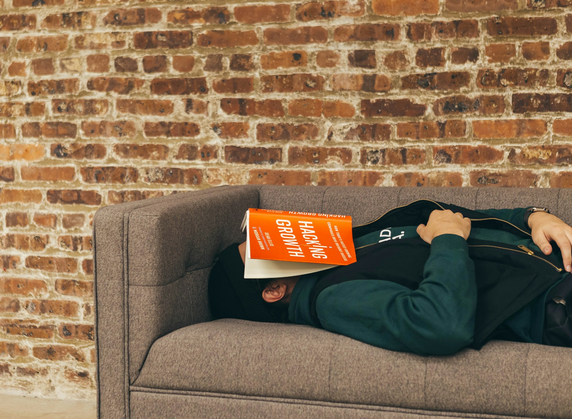 man sleeping on couch with a book on his face